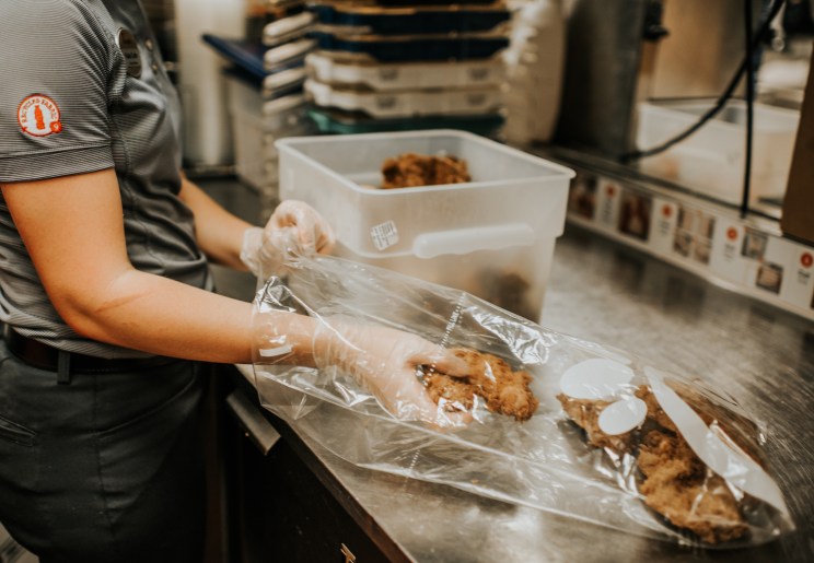 A team member packs chicken into bags for donation.