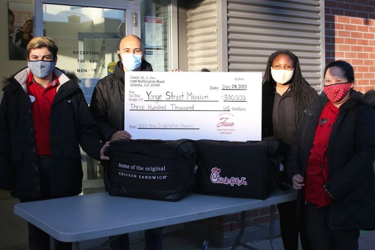 A group of people outside holding an oversized check