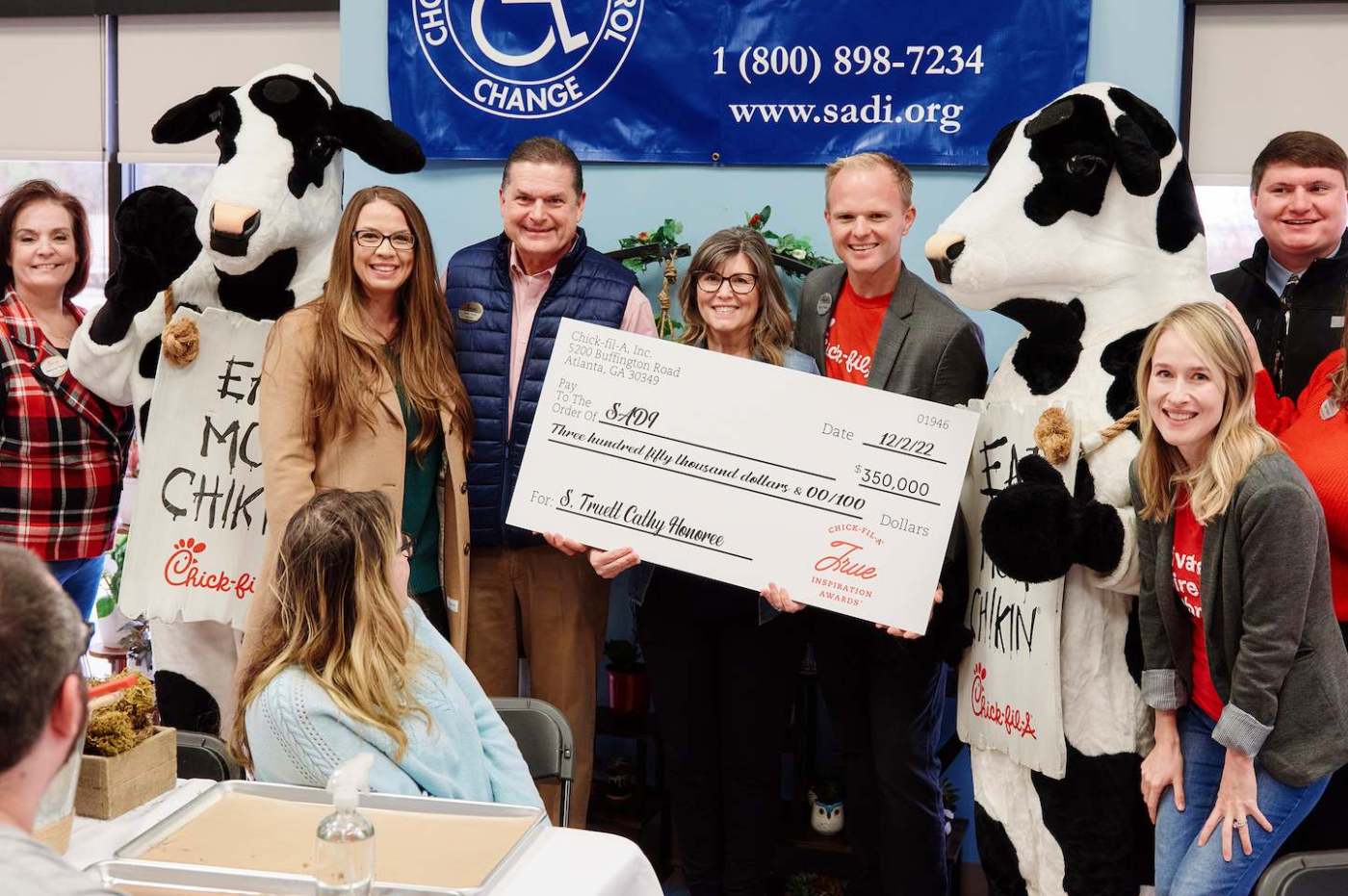 People holding a large presentation check with two cow mascots.