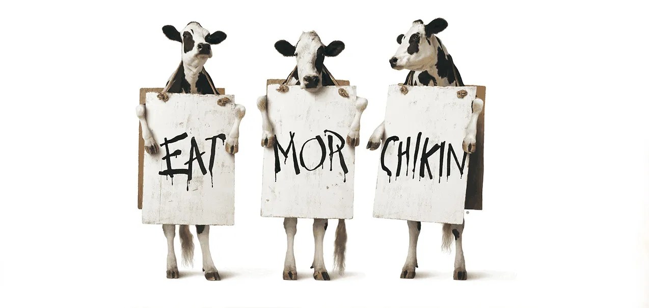 Three cows holding signs that say "EAT MOR CHIKIN."