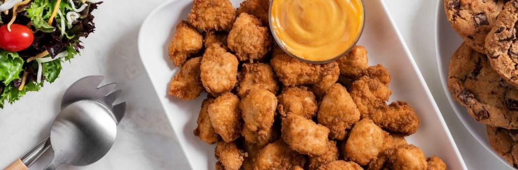 Catering trays including salad, cookies and chicken nuggets.