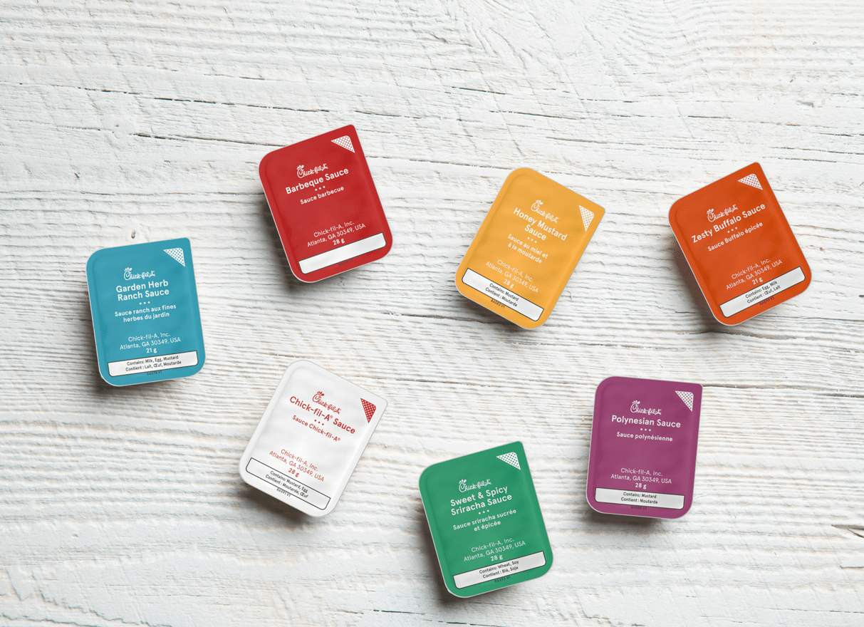 Assorted Chick-fil-A sauce packets on a white wooden surface.