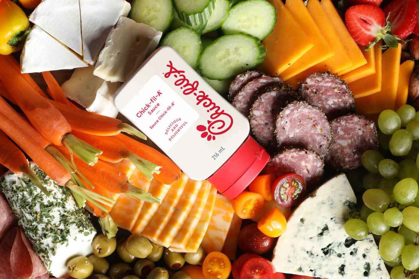 Assorted food platter with Chick-fil-A sauce, cheeses, meats, fruits, and vegetables.
