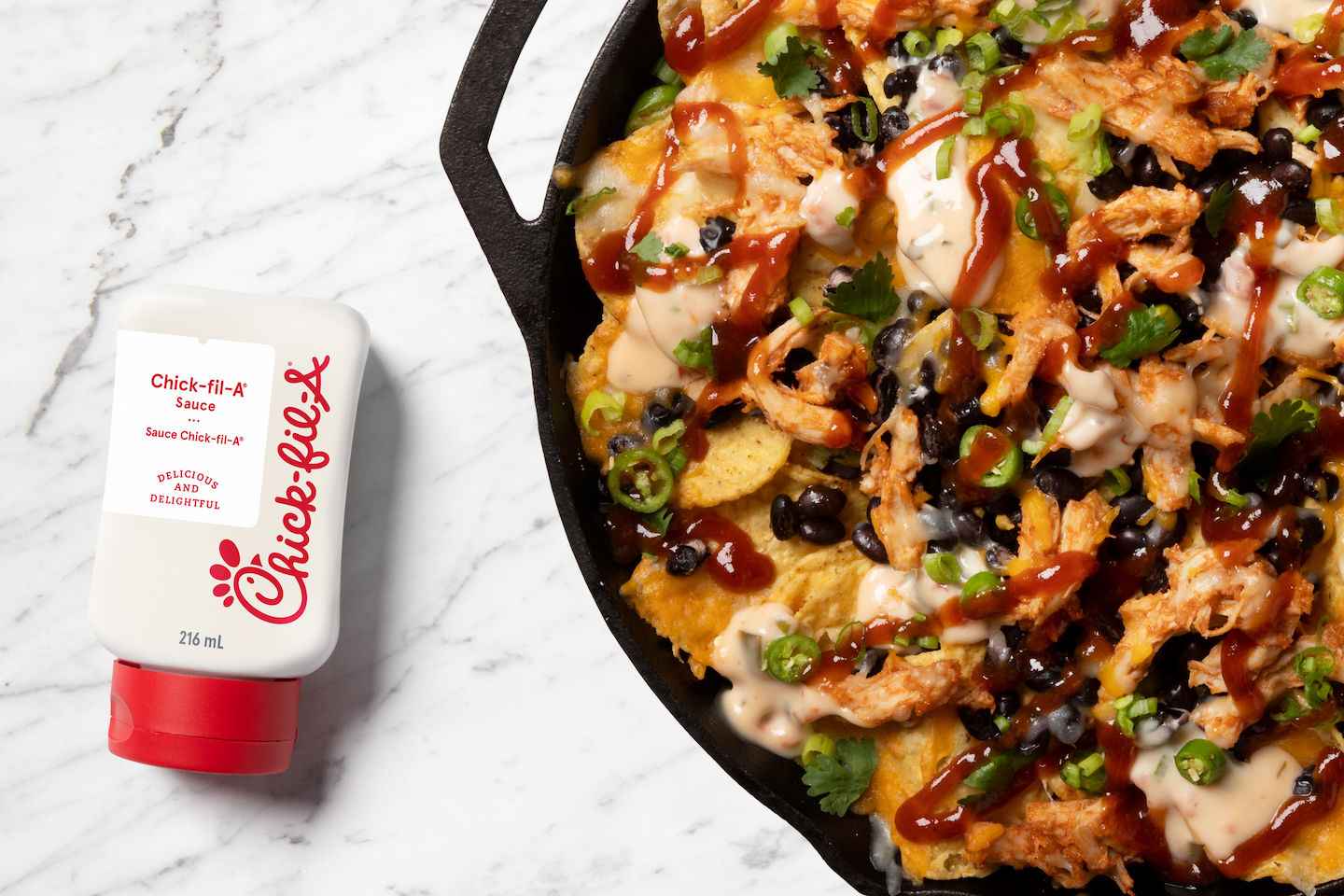 Chick-fil-A sauce container next to a skillet of loaded nachos with toppings.