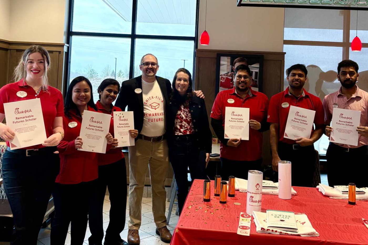 Group of people at Chick-fil-A, some holding "Remarkable Futures Scholar" certificates.