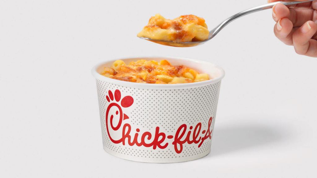 Spoon lifting mac and cheese from a Chick-fil-A branded container.