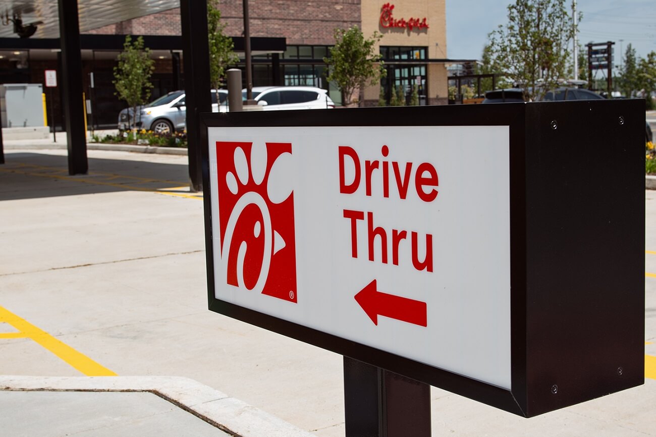 Drive-thru sign with Chick-fil-A branding in a parking lot.