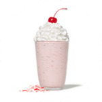 A Peppermint Chip Milkshake with whipped cream and a cherry, in a glass with candy cane pieces.