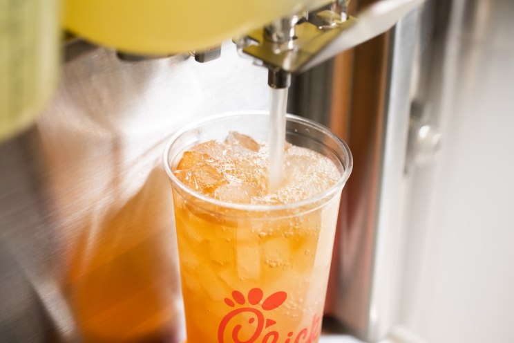 Cup being filled with a Sunjoy beverage and ice from a drink dispenser.