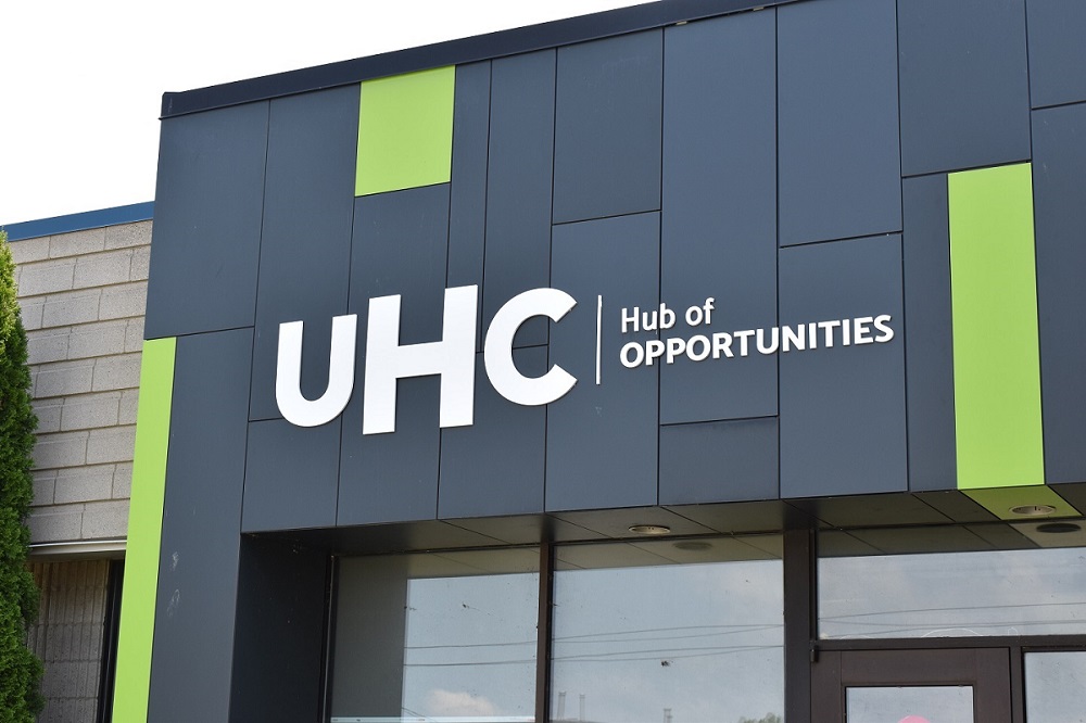 Building facade with "UHC Hub of OPPORTUNITIES" written in white on dark panels with green accents.