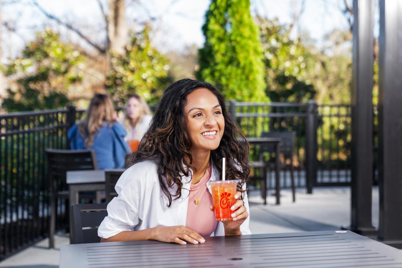Smiling woman sitting outdoors holding a Chick-fil-A Sunjoy.