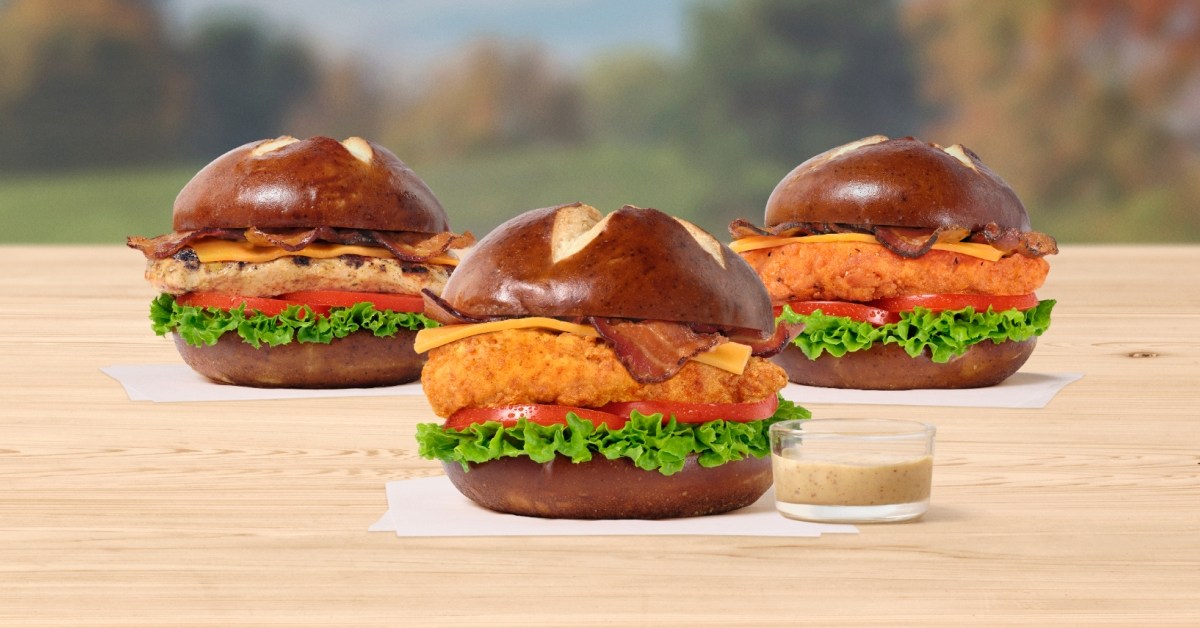 Three Pretzel Cheddar Club Sandwiches sitting on white napkins.
